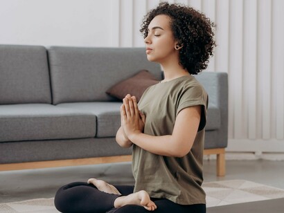 Sentada no chão, a mulher permanece em uma posição de yoga, voltada para um momento de concentração. A meditação é apresentada no artigo como uma possibilidade de acessar novos estados internos e transformar a maneira de experimentar a realidade