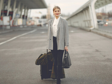 Smiling woman walking through the airport with her suitcase, relocating overseas