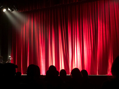 A salon with red theatre chairs facing deep red curtains