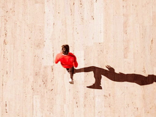 A man in red joggers, with his shadow cast from above