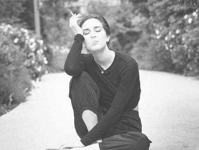 A woman sitting on the ground having a cigarette smoke
