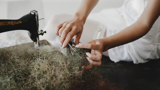 A woman sits at a table, working with a sewing machine to create bio-based textiles, promoting sustainable, circular, and eco-friendly fashion with biodegradable fabrics