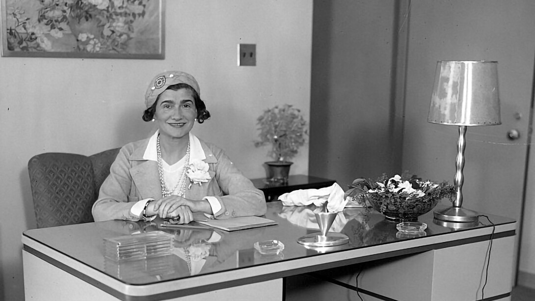 Coco Chanel sitting at a desk during a visit to Los Angeles, USA