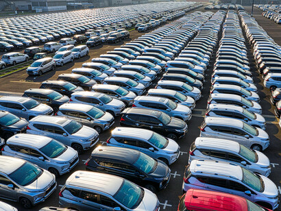 Aerial view of a large parking lot filled with unsold cars, symbolizing global car production