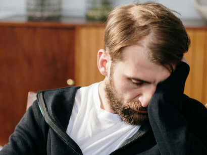 A blond man, holding his head in his hands in sorrow