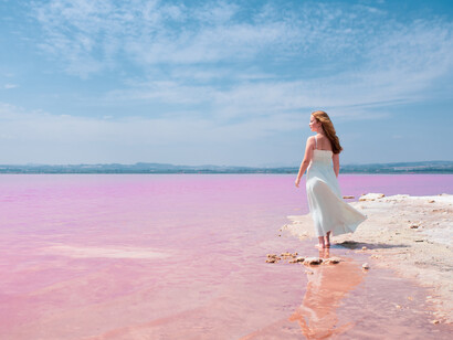 Dressed in white, a woman walks gracefully on the surface of a mesmerizing pink lake