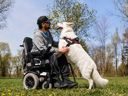 A man with a disability enjoying a peaceful walk through the park with his trained service dog by his side