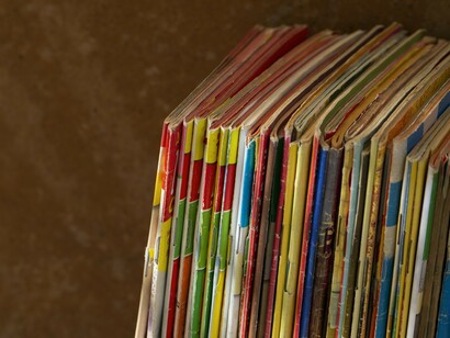 Rows of colorful publications symbolize the spread of dissenting voices, with Ramparts Magazine at the forefront of New Left journalism