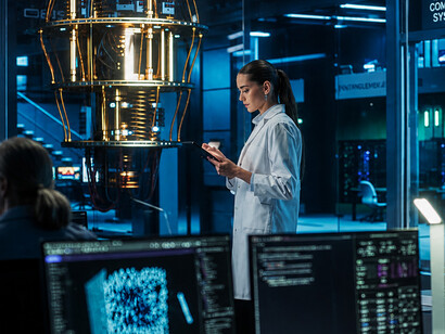 A female computer engineer examines a quantum computer in a high-tech scientific laboratory while analyzing research and development data on her tablet