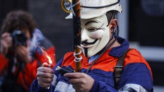 Un minero enmascarado enciende un petardo durante una protesta en Asturias