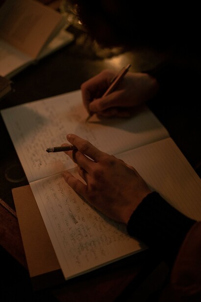 Someone journaling, while smoking a cigarette