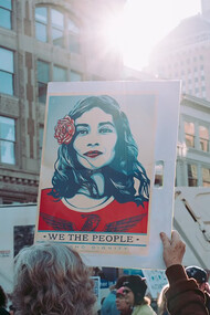 A person holding a 'We the People' sign, surrounded by a crowd—this iconic sign became a symbol of the Women's Marches held around the world