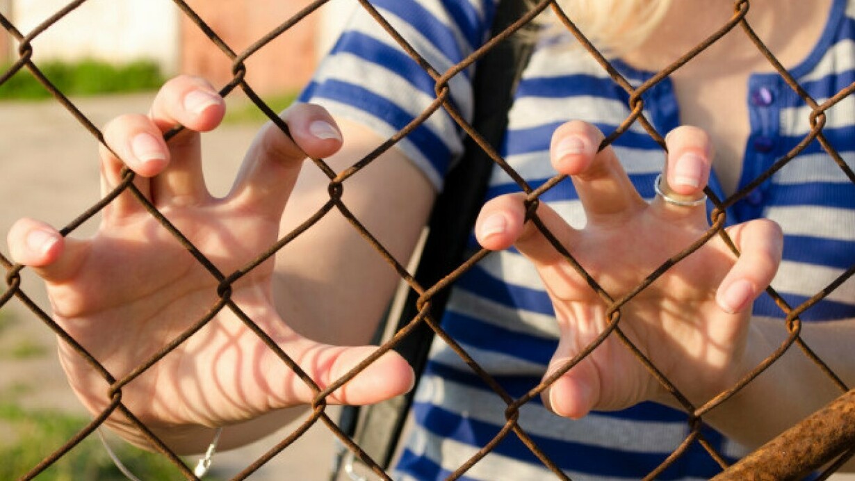 Una joven atrapada detrás de una reja