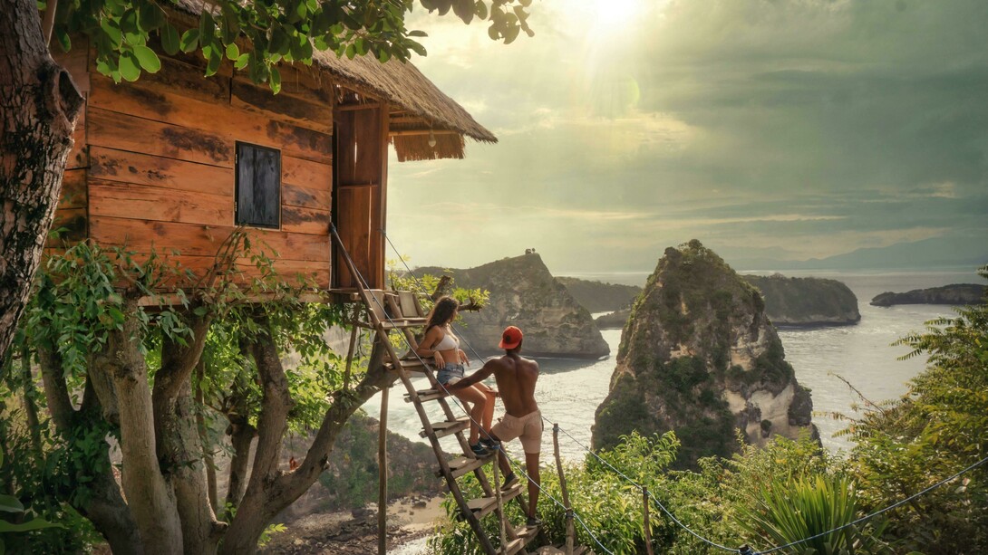 A couple sits on a brown wooden ladder in Bali, Indonesia, enjoying a quiet moment