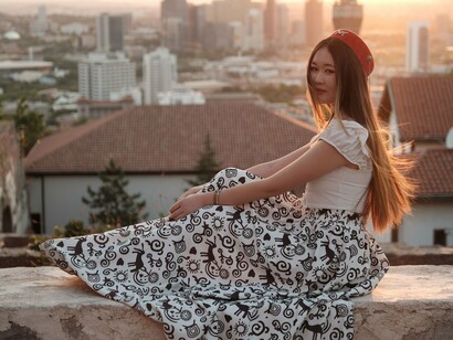 A woman seated in peaceful reflection as the city stretches behind her, reflecting the search for authenticity amid society's expectations