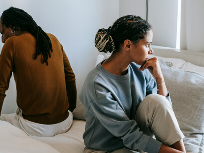 A concerned couple sitting apart on a bed during a moment of misunderstandin