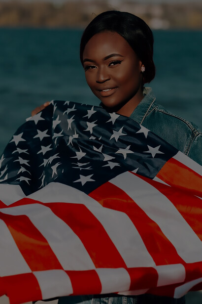 A Black woman proudly holds American flags in her hands, embodying a sense of patriotism and pride
