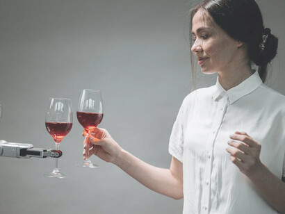 In the company of an AI-driven robot, a woman enjoys a glass of wine with a touch of sophistication