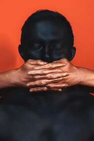 A white man covering a Black person’s face with his hands