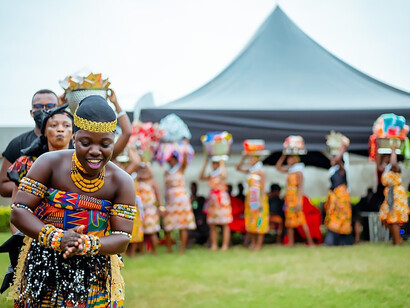 In Accra, Ghana, a woman adorned in the vibrant attire of her tribe graces the scene with an enchanting dance