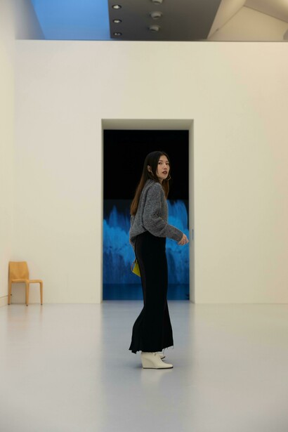 A woman seen from behind walking through a modern museum with a white interior