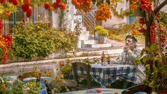 A man sitting at a table surrounded by gardens, tomatoes, plants - nature