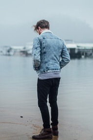 Man standing alone on the beach, looking at his reflection 