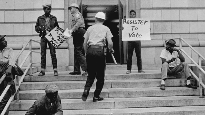 Sheriff Jim Clark arrests two demonstrators who displayed placards on the steps of the federal building in Selma, 1963. Gelatin silver print, 11 x 14 inches. © Danny Lyon, New York & Magnum Photos, New York / Courtesy Edwynn Houk Gallery, New York.