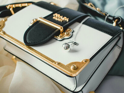 A carefully styled handbag beside muted satin tones, representing the sophistication behind true luxury