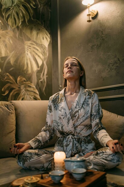 A woman sits quietly on a couch, practicing mindfulness in a calm, softly lit interior