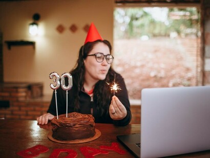 A woman joyfully celebrating her 30th birthday via video call on her laptop, reflecting on her independence and the freedom that comes with entering her 30s