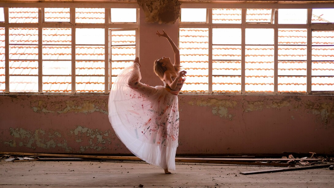 Uma bailarina encontra, entre a luz e as marcas do tempo, a delicadeza de um gesto suspenso. Há movimentos que o corpo aprende, mas há outros que parecem nascer de um fogo interior que o tempo não consegue apagar. Sob a luz que atravessa o antigo espaço, a bailarina transforma o próprio corpo em gesto e presença. Como na vida, a dança não interrompe o tempo: encontra novas formas de continuar