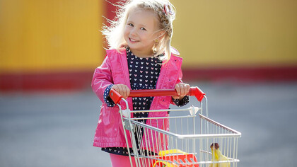 A happy, smiling child shopping with a cart, learning about ingredients and choosing healthy food