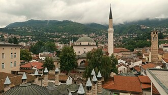Vista Panorâmica Da Arquitetura Histórica De Sarajevo. Ao chegar a Sarajevo, fui imediatamente arrebatada pela paisagem que circunda a cidade e pela arquitetura variada, refletindo séculos de dominação otomana, austro-húngara e, mais recentemente, os traços deixados pela antiga Iugoslávia. Caminhar por suas ruas é como folhear as páginas de um livro de história vivo