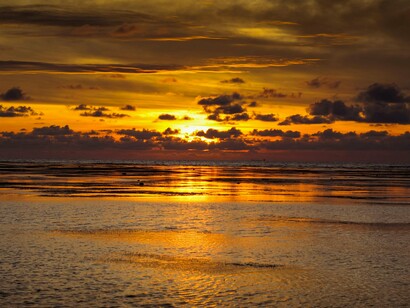 Praia turística no pôr-do-sol. Desde os primórdios sempre soubemos que alguns estão mais dispostos a viajar do que outros, mas se tem algo que fica extremamente claro para mim, é que nós não fomos feitos para estar parados nem mesmo quando achamos que estamos. Nós estamos sempre nos movendo, pelas mais diferentes razões