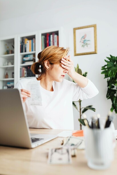 Woman holds her face after seeing her bills