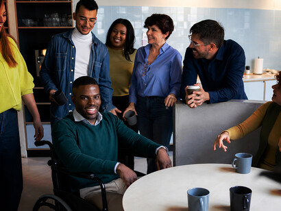 Colleagues from diverse cultural backgrounds share a relaxed coffee break in a contemporary office environment