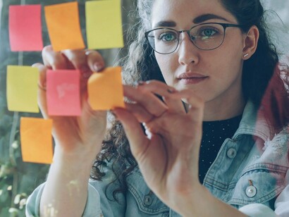 A young woman arranging colourful notes on a glass board, representing the importance of including younger perspectives in climate decision-making