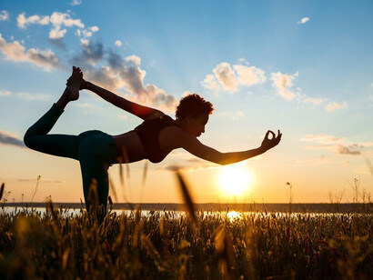 A serene silhouette of a girl engaging in yoga at sunrise, fostering mindfulness and meditation in a tranquil field, embracing the beauty of nature