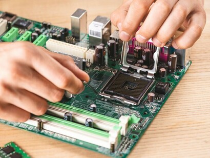 An IT technician repairing hardware equipment on a wooden table, including neuromorphic chips