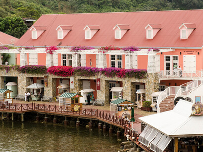 A wooden boardwalk connects various small kiosks, stores, and dining options along the water