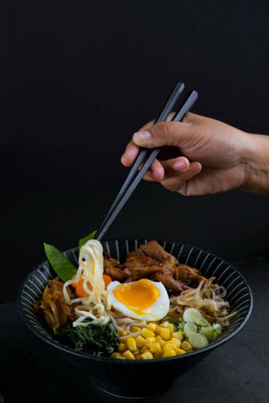 A steaming bowl of ramen against a dark backdrop