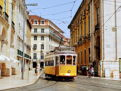 Sunny day in Lisbon, Portugal, yellow and white tram glides along the road
