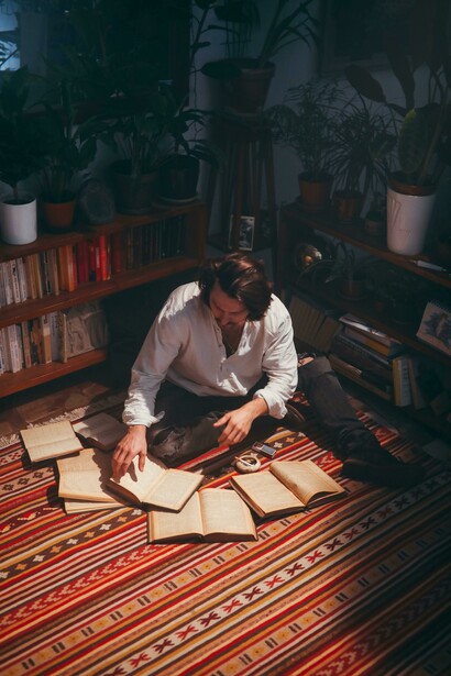 A vintage scene of a man seated on a red carpet, absorbed in poetry