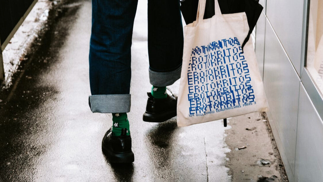 Una chica sostiene su 'tote bag' blanca. 'Tote' viene del verbo 'to tote', que significa «llevar»