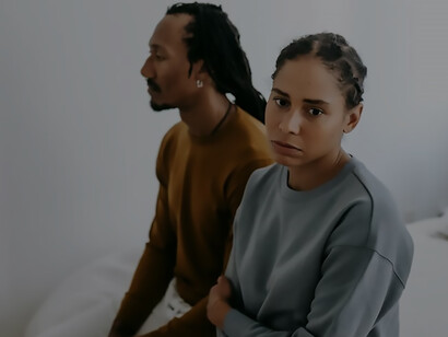 Amidst a shared disquiet, a couple sits on a bed, accentuating the vital need for open and empathetic communication to navigate challenges and nurture a resilient and harmonious relationship