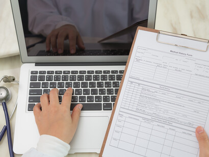 Medico che riporta a computer dati di una cartella clinica