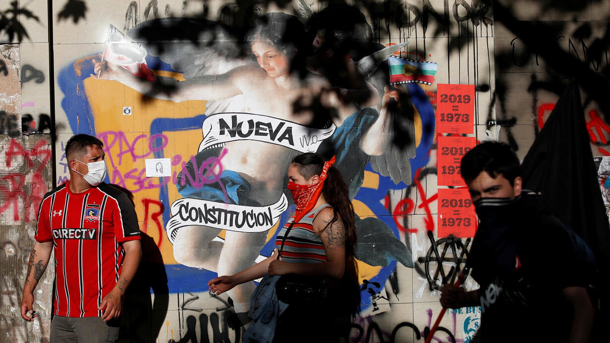 Manifestantes frente al grafiti que se volvió emblema del deseo de una nueva Constitución en Santiago, Chile