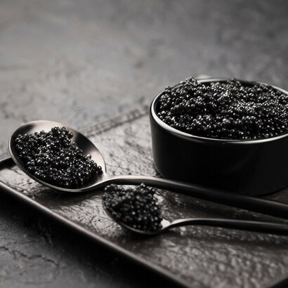 Black caviar served in a bowl, accompanied by spoons and a ladle