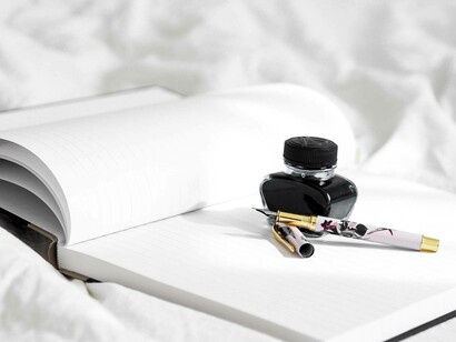 A pen, a pot of ink and a blank page of a writer's journal